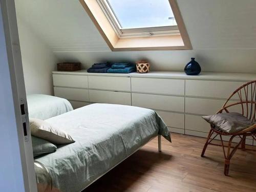 ein Schlafzimmer mit einem Bett, einem Fenster und einem Stuhl in der Unterkunft Maison moderne à 2 pas des plus jolies plages ! in Saint-Pabu