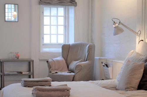 a bedroom with a chair and a bed and a lamp at Store Ejlstrup Bed & Breakfast in Odense
