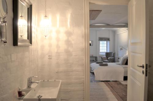 a bathroom with a sink and a room with a bed at Store Ejlstrup Bed & Breakfast in Odense