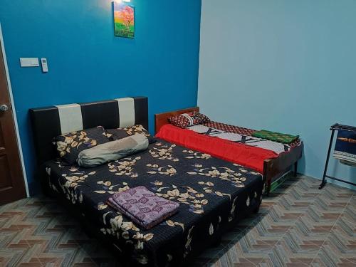 a bedroom with two beds and a blue wall at SR KAMPAR HOMESTAY in Kampar