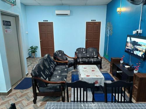 a living room with a table and chairs and a tv at SR KAMPAR HOMESTAY in Kampar