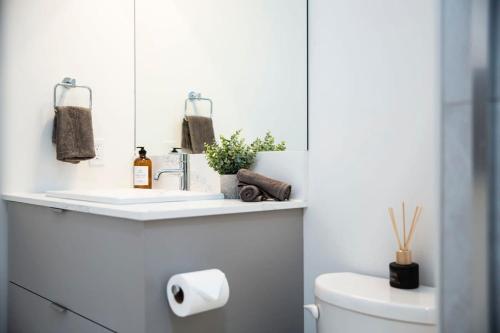 a white bathroom with a sink and a toilet at Domino Condo - Bunk Bed & Hot Tub in Revelstoke