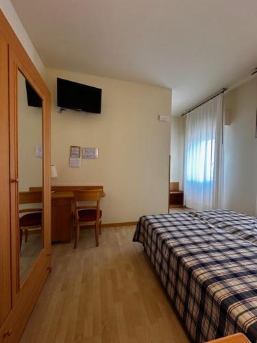 a hotel room with a bed and a desk and a window at Hotel Ponte Molo in Porto Tolle