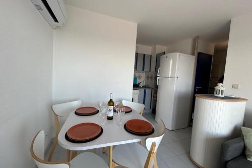 une petite cuisine avec une table blanche avec deux chaises et un réfrigérateur blanc dans l'établissement 180 panoramic terrace, à Frontignan