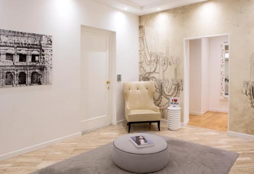 a living room with a chair and a ottoman at Via Del Corso Home Roma in Rome