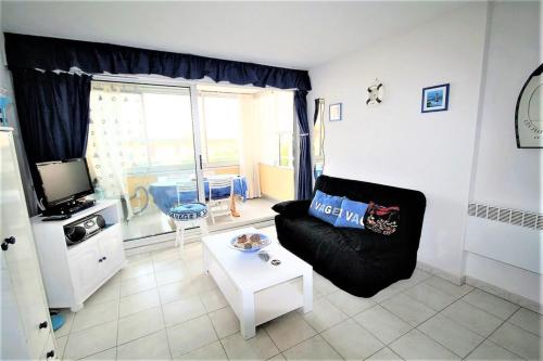 uma sala de estar com um sofá preto e uma mesa em The sea within sight em Frontignan