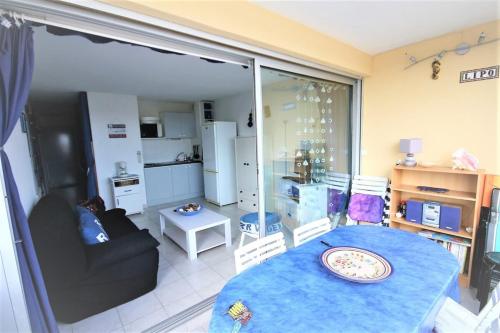 uma sala de estar com uma mesa azul e uma cozinha em The sea within sight em Frontignan