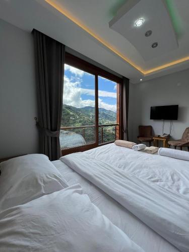 a bedroom with a large bed with a large window at Peruma otel bungalov in Çamlıhemşin