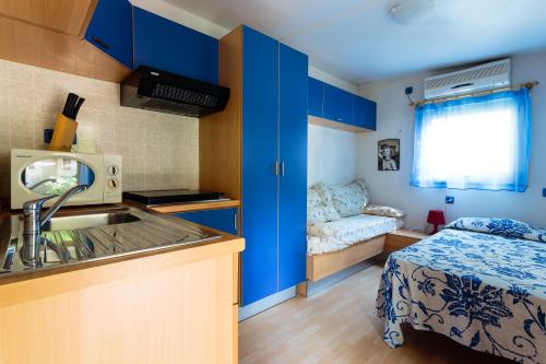 eine Küche mit blauen Schränken und einem Waschbecken im Zimmer in der Unterkunft Arcobaleno Village H in Marina di Bibbona