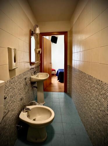 a bathroom with a sink and a toilet and a mirror at Hotel Ponte Molo in Porto Tolle