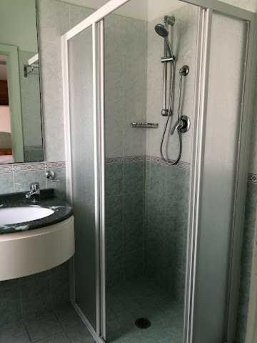 een douche met een glazen deur naast een wastafel bij HOTEL AUGUSTUS in Gatteo a Mare