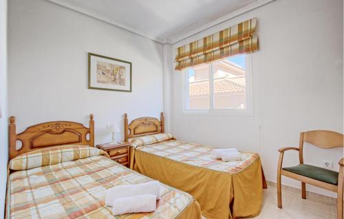 サンタ・ポラにあるNice Home In Santa Pola With Swimming Poolのベッドルーム1室(ベッド2台、椅子、窓付)