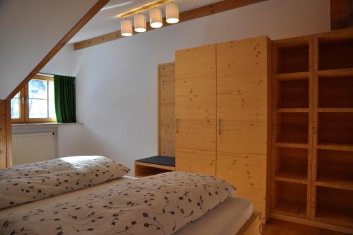 a bedroom with a bed and some wooden cabinets at AlpenFerienLandhaus Müller in Rettenberg