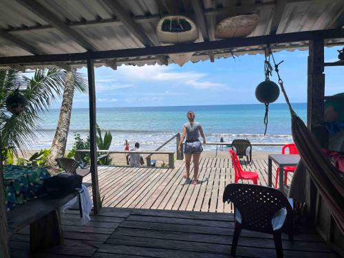 a woman standing on a wooden deck looking at the beach at CABAÑA TELLO SURF in Nuquí