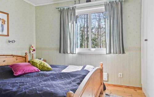 a bedroom with a bed with a blue comforter and a window at 2 Bedroom Awesome Home In Örkeljunga in Orkelljunga