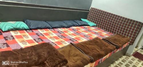a bed with a quilt and pillows on it at Gehelot DharmShala in Ujjain