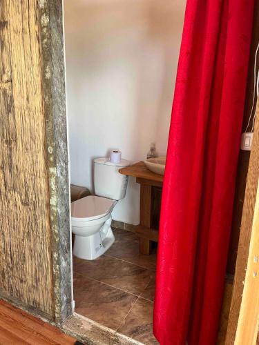 a bathroom with a toilet and a red curtain at CABAÑA TELLO SURF in Nuquí