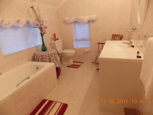a bathroom with a tub and a sink and a toilet at Avondsrus Guesthouse in Bettyʼs Bay