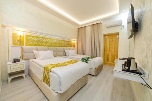 a hotel room with two beds and a television at Arslan Boutique Hotel in Khiva