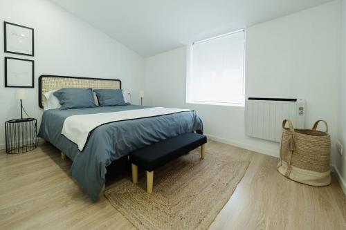 a white bedroom with a bed with blue pillows at Ático Isabel, diseño y calidez junto a la Muralla Romana in Lugo