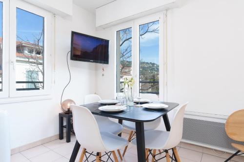 une salle à manger avec une table noire et des chaises blanches dans l'établissement Le Calmette By ApiRent #Central #Lumineux #Calme #Wifi, à Cannes
