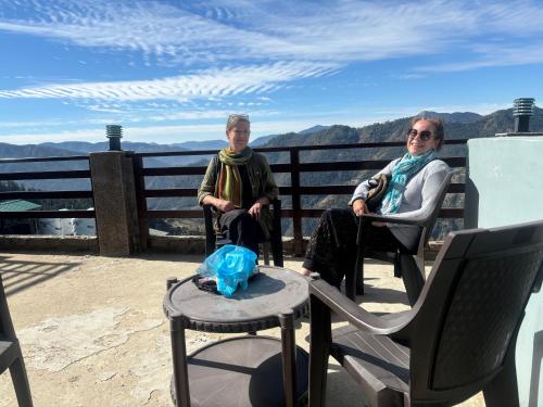 dwie starsze kobiety siedzące na krześle na balkonie w obiekcie Mountain and peace w mieście Shimla