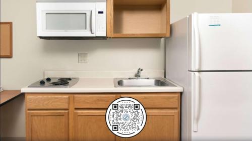 a kitchen with a white refrigerator and a sink at WoodSpring Suites St Louis Arnold in Arnold