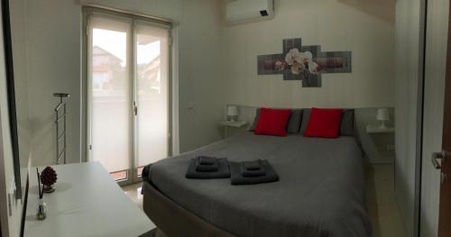 a bedroom with a large bed with red pillows at Bella Recanati Apartment a Giardini Naxos in Giardini Naxos