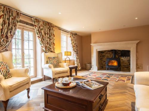 a living room with a fireplace and chairs and a table at Ashworth House in Leafield