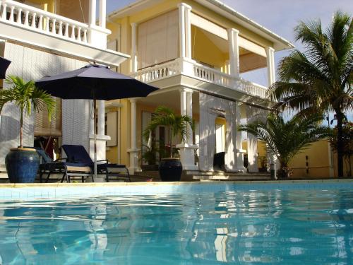 a swimming pool in front of a house with an umbrella at Résidence Syrina 1 in Trou aux Biches