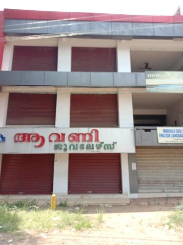 un bâtiment avec des portes de garage rouges et blanches dans l'établissement Kailas 4, à Kollam