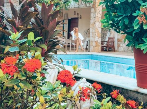 a woman sitting in a chair next to a swimming pool at La Casa de las Lunas in Chichén-Itzá