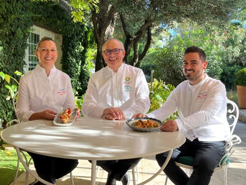 three chefs sitting at a table with bowls of food at Auberge de Cassagne & Spa in Le Pontet
