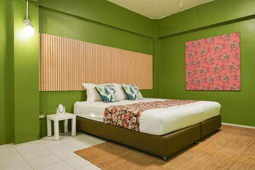 1 dormitorio con 1 cama en una pared verde en โกอินน์ พระบรมมหาราชวัง สถานีสามยอด - GO INN The Grand Palace en Bangkok