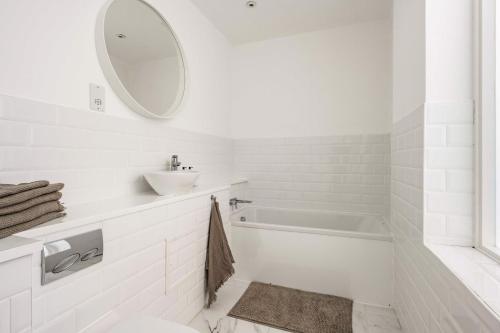 a white bathroom with a sink and a tub at The Old Post Office - Norfolk Holiday Properties in Norwich