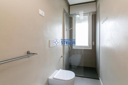 a bathroom with a toilet and a window and a shower at Condominio Secchiati in Lido di Jesolo