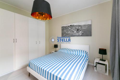 a bedroom with a bed with a blue and white striped sheets at Condominio Secchiati in Lido di Jesolo