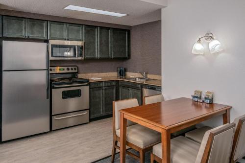 a kitchen with a wooden table and a stainless steel refrigerator at Residence Inn by Marriott Chesapeake Greenbrier in Chesapeake