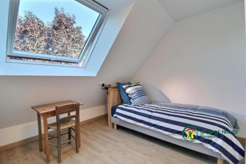een kleine slaapkamer met een bed en een raam bij La Fleur de Vie in Pluneret