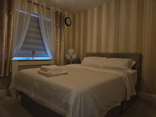 ein Schlafzimmer mit einem Bett und einem Fenster mit einer Uhr in der Unterkunft Comfortable Short Stay in Dublin in Dublin