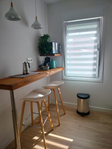 a kitchen with a counter with stools and a window at Piso en Laracha inicio Costa da Morte in Laracha
