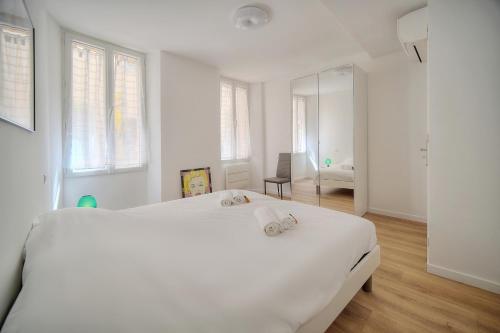 - une chambre blanche avec un grand lit blanc et 2 serviettes dans l'établissement Charmant 3 pieces centre ville A2B243, à Cannes