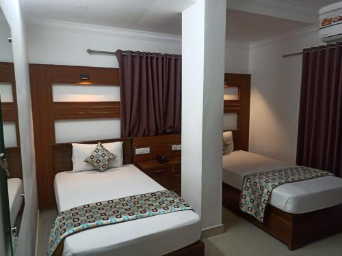 a small bedroom with two beds and a window at Rieva Residency in Kottayam