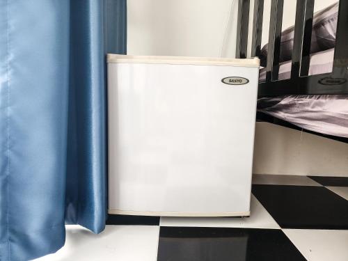 a small refrigerator sitting on a floor next to a bed at Noir Cafe And Hostel Chinatown Bangkok in Chinatown