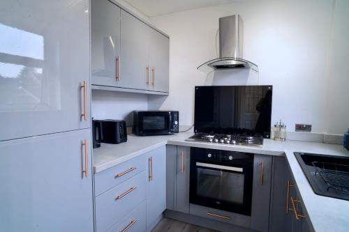 uma cozinha com armários brancos e um forno com placa de fogão em Modern 2 Bedroom Home in Edinburgh Free Parking em Edimburgo