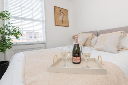 a tray with a bottle of wine and two glasses on a bed at 2 Bed Exceptional Stay in Reading