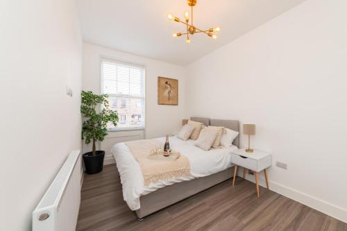 a white bedroom with a bed and a window at 2 Bed Exceptional Stay in Reading