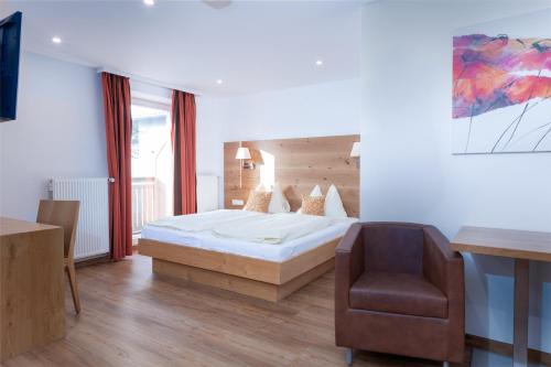 a bedroom with a bed and a chair at Hotel Schönberger in Nussdorf am Attersee