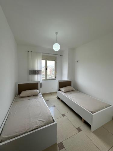2 Betten in einem Zimmer mit weißen Wänden in der Unterkunft Cozy and comfortable apartment in Durrës
