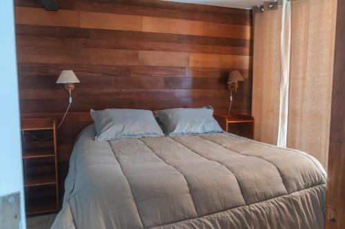 a bedroom with a large bed with wooden walls at Cabañas El Bosque in Maitencillo